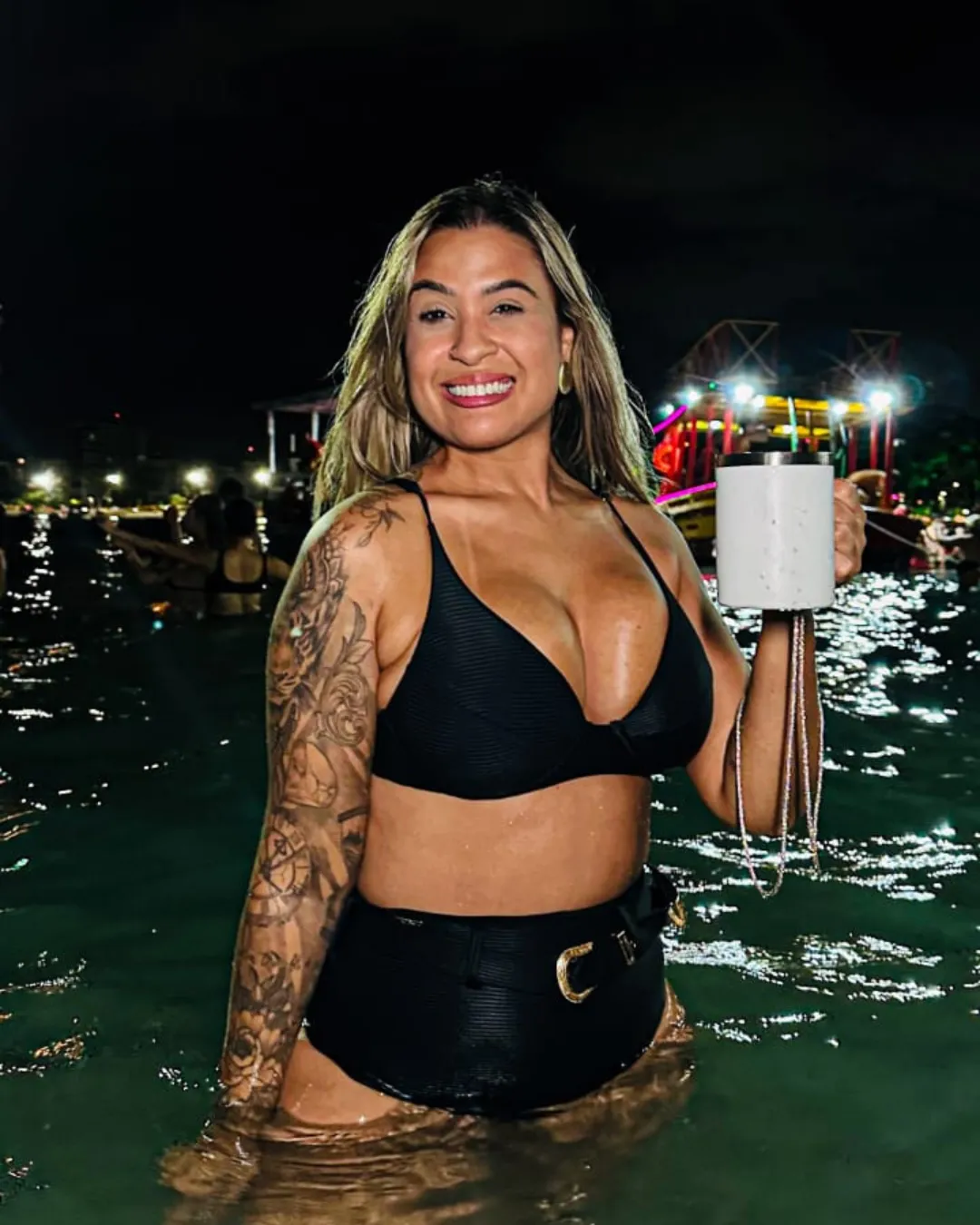 Cliente na água à noite, com o barco iluminado ao fundo